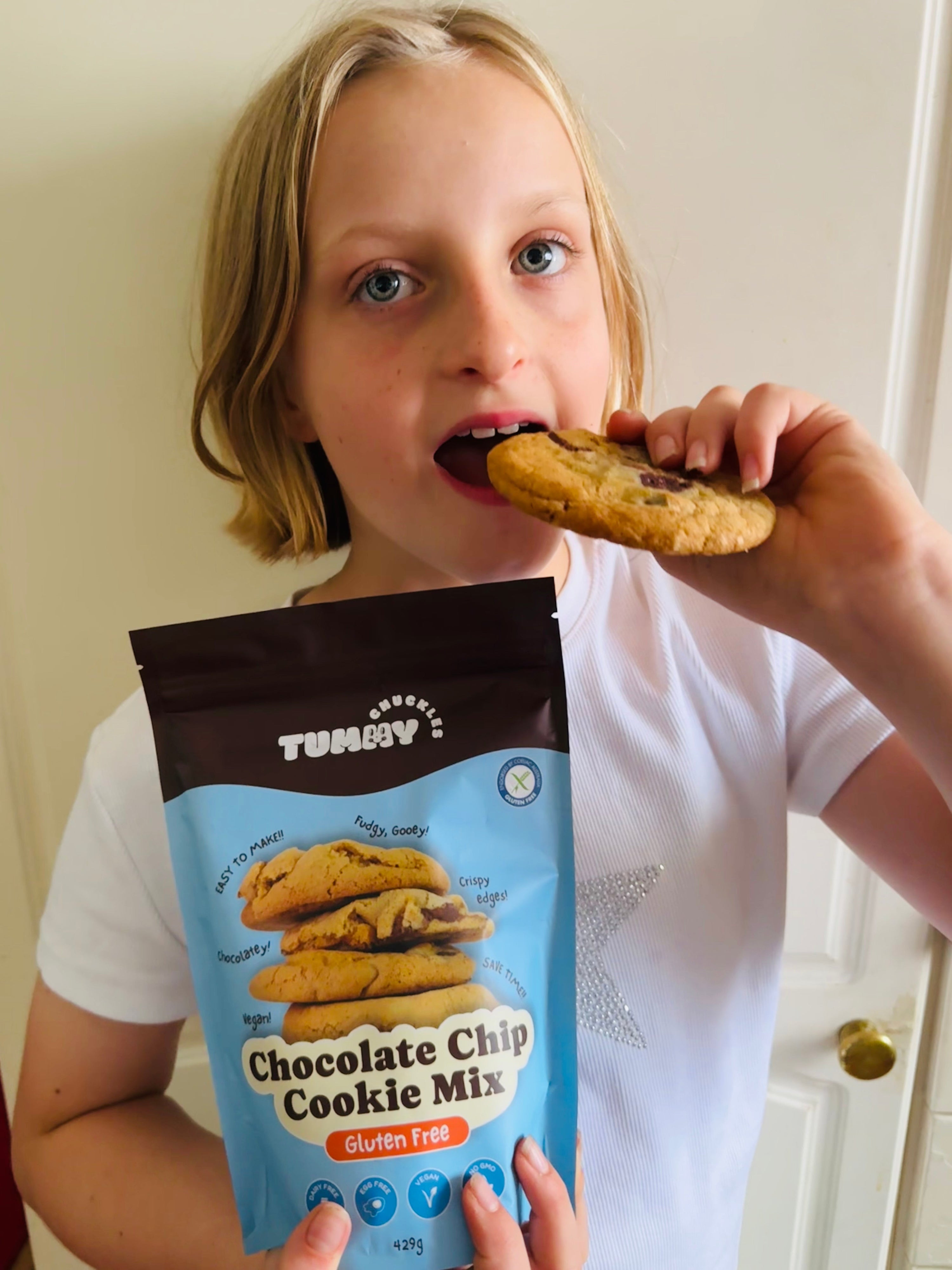 Child eating a cookie with a Tummy Chocolate Chip Cookie Mix package
