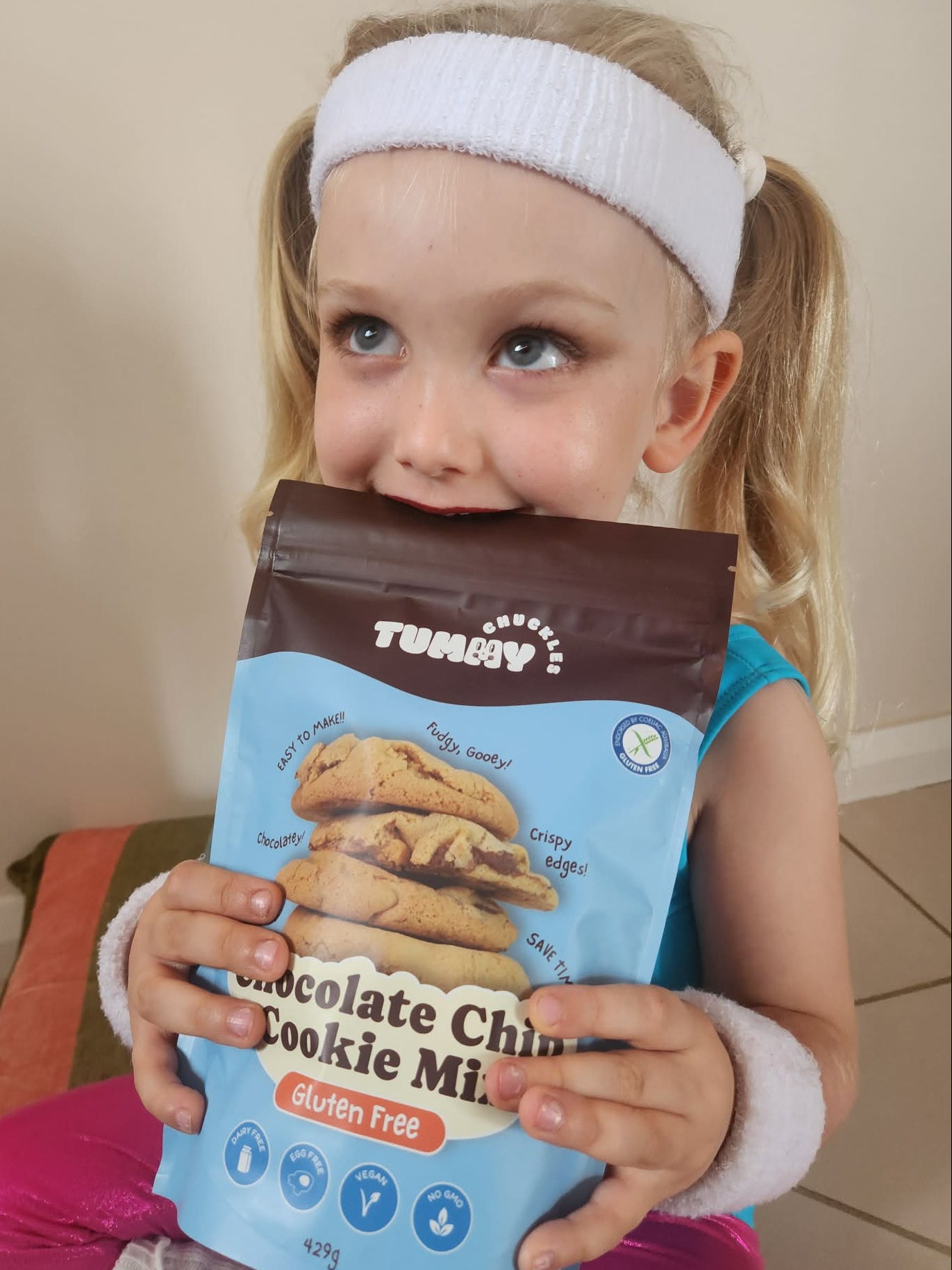 Child smiling and holding Tummy Chuckles Chocolate Chip Cookie Mix _ gluten free