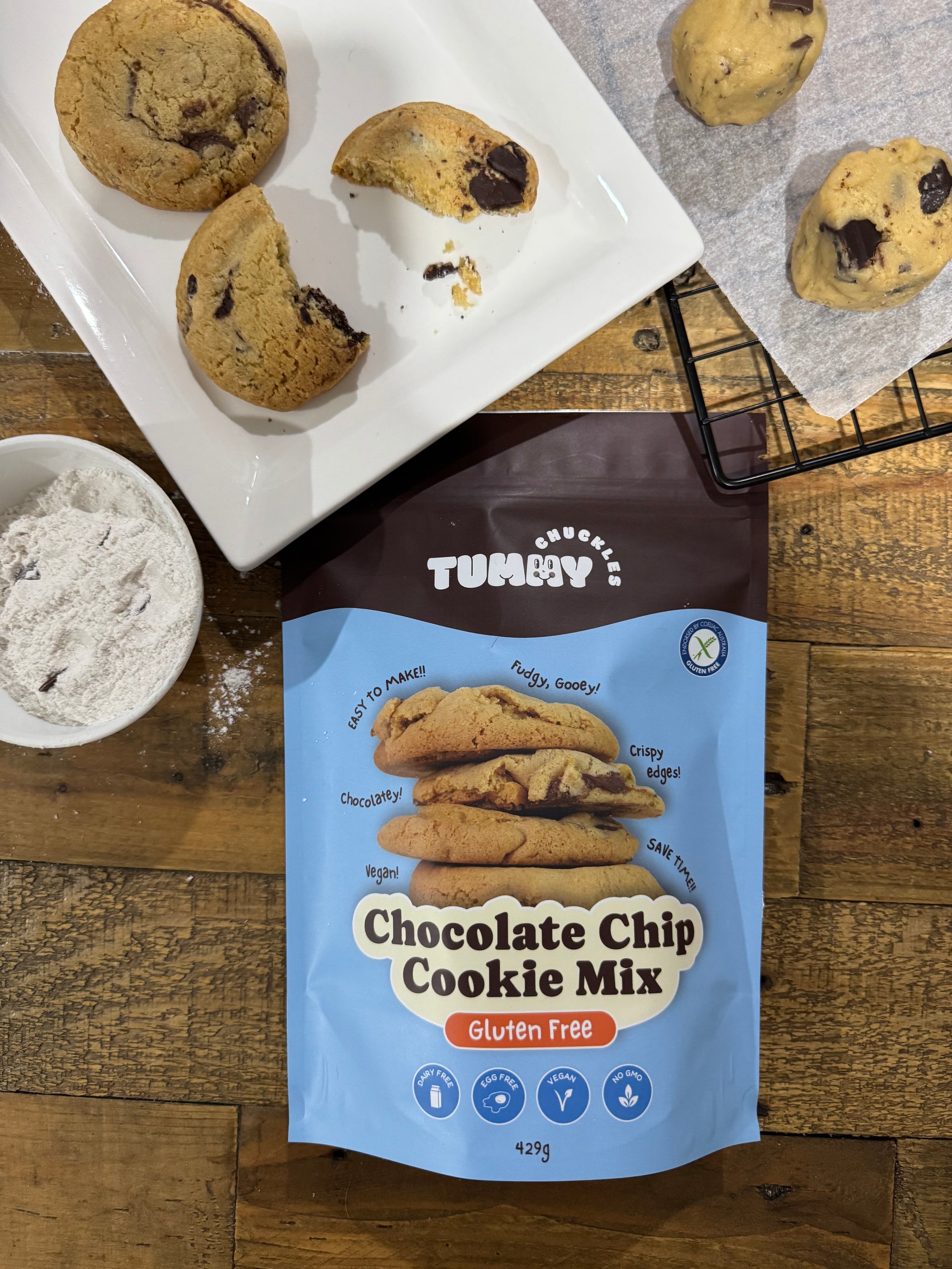 Tummy Chuckles chocolate chip cookie mix package with cookies on a wooden surface